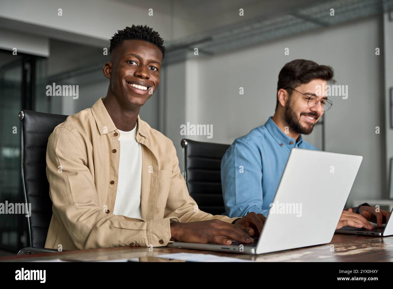 Professioneller junger glücklicher afrikanischer Mann, der mit einem Team im Büro arbeitet, Porträt. Stockfoto