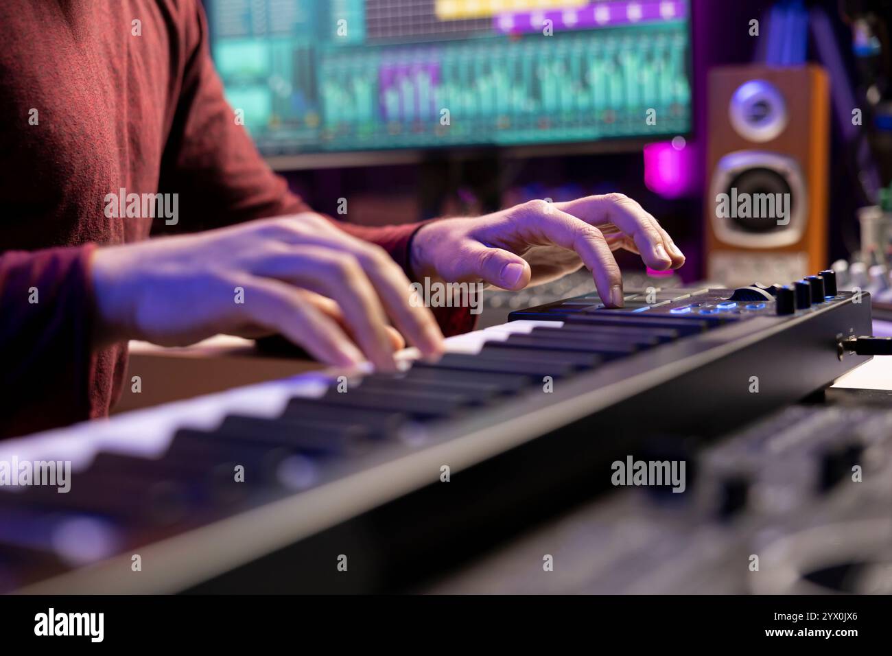 Der Künstler spielt Klaviernoten und bearbeitet die Klangqualität von Audioaufnahmen im Heimstudio, wobei er die elektronische Tastatur bedient. Musikproduzent verwendet Midi-Controller, um Klänge zu manipulieren. Stockfoto