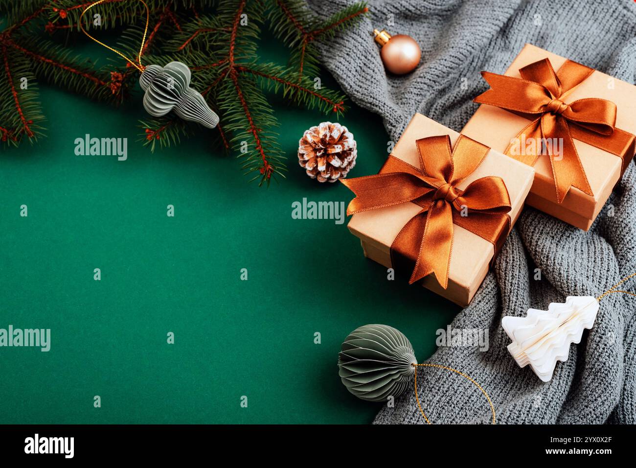 Geschenkboxen und festliche Dekorationen auf dunkelgrünem Hintergrund mit Tannenzweigen und Ornamenten. Draufsicht, flach, Kopierbereich. Stockfoto