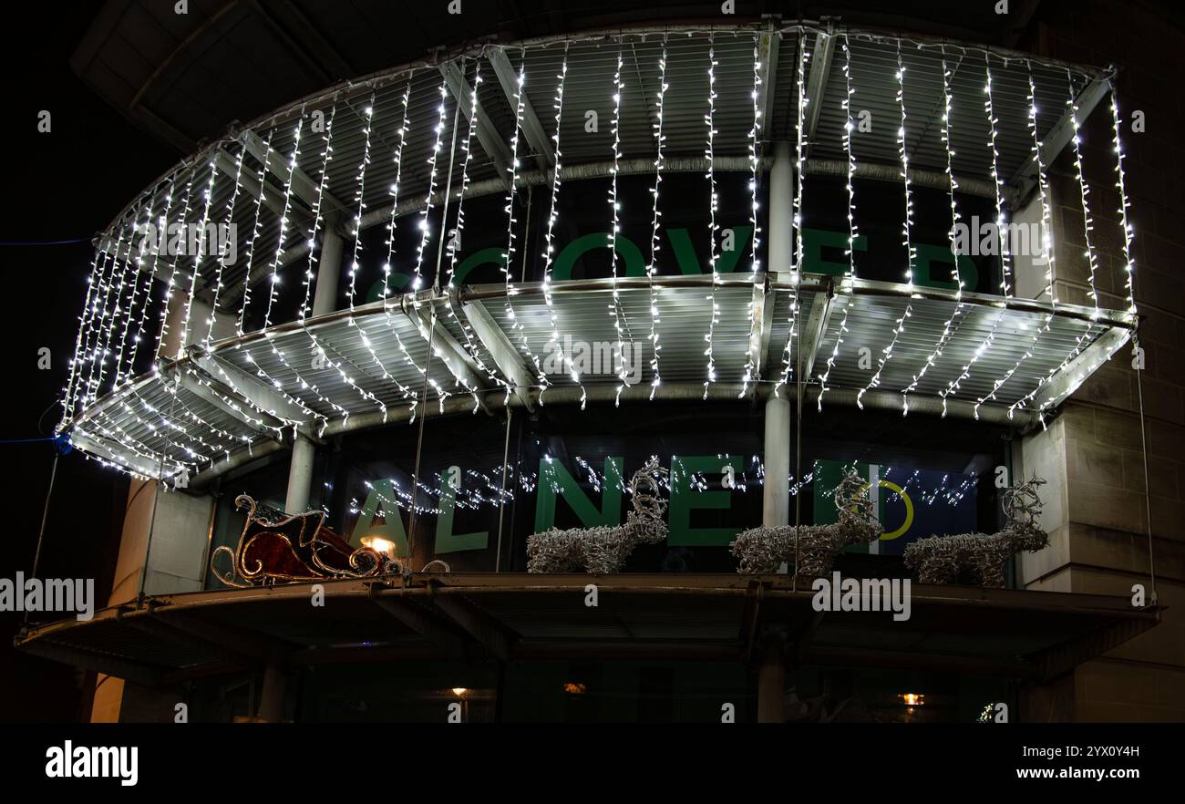 Nächtlicher Blick auf ein Gebäude mit weißen Weihnachtslichtern und dekorativem Rentier und Schlitten auf einem Balkon im Bibliotheksgebäude Calne Wiltshire UK Stockfoto