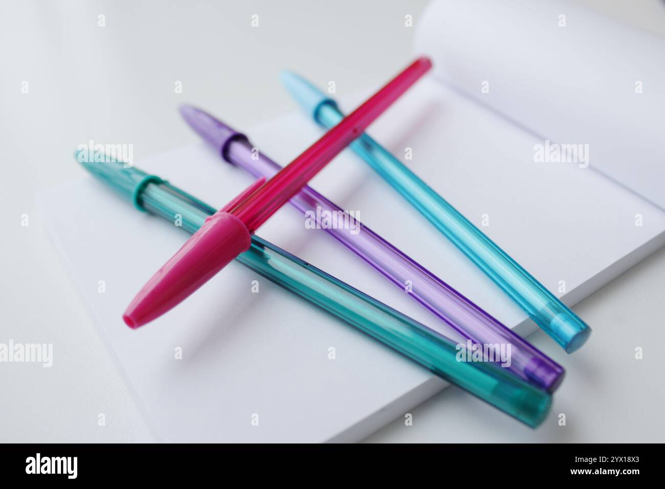 Vier coole Farbstifte auf einer leeren Notizblockseite. Grün, lila, rosa und blau. Kreative Schreibwaren, zurück zur Schule, Kunstklassenkonzept. Stockfoto
