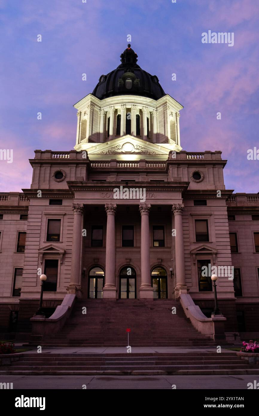 Blick auf die Stufen des Kapitolgebäudes des Bundesstaates South Dakota in Pierre bei Sonnenuntergang mit einem rosafarbenen Himmel dahinter Stockfoto