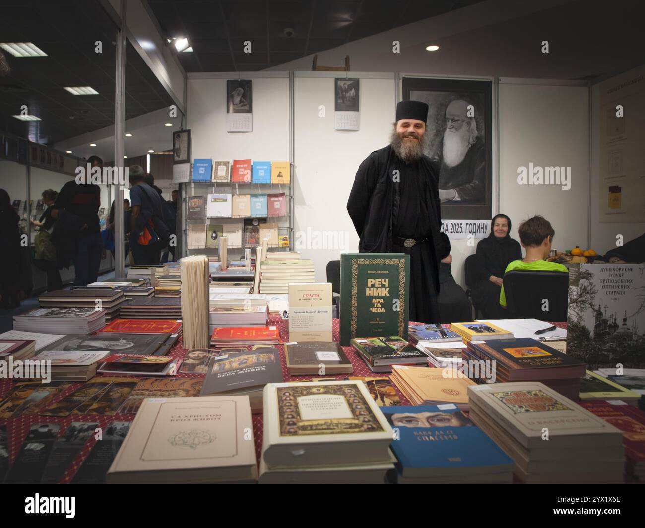 BELGRAD, SERBIEN - 20. OKTOBER 2024: Ein serbisch-orthodoxer Priester steht in der Nähe religiöser Literatur in einem lokalen Buchladen, umgeben von religiösen Büchern Stockfoto