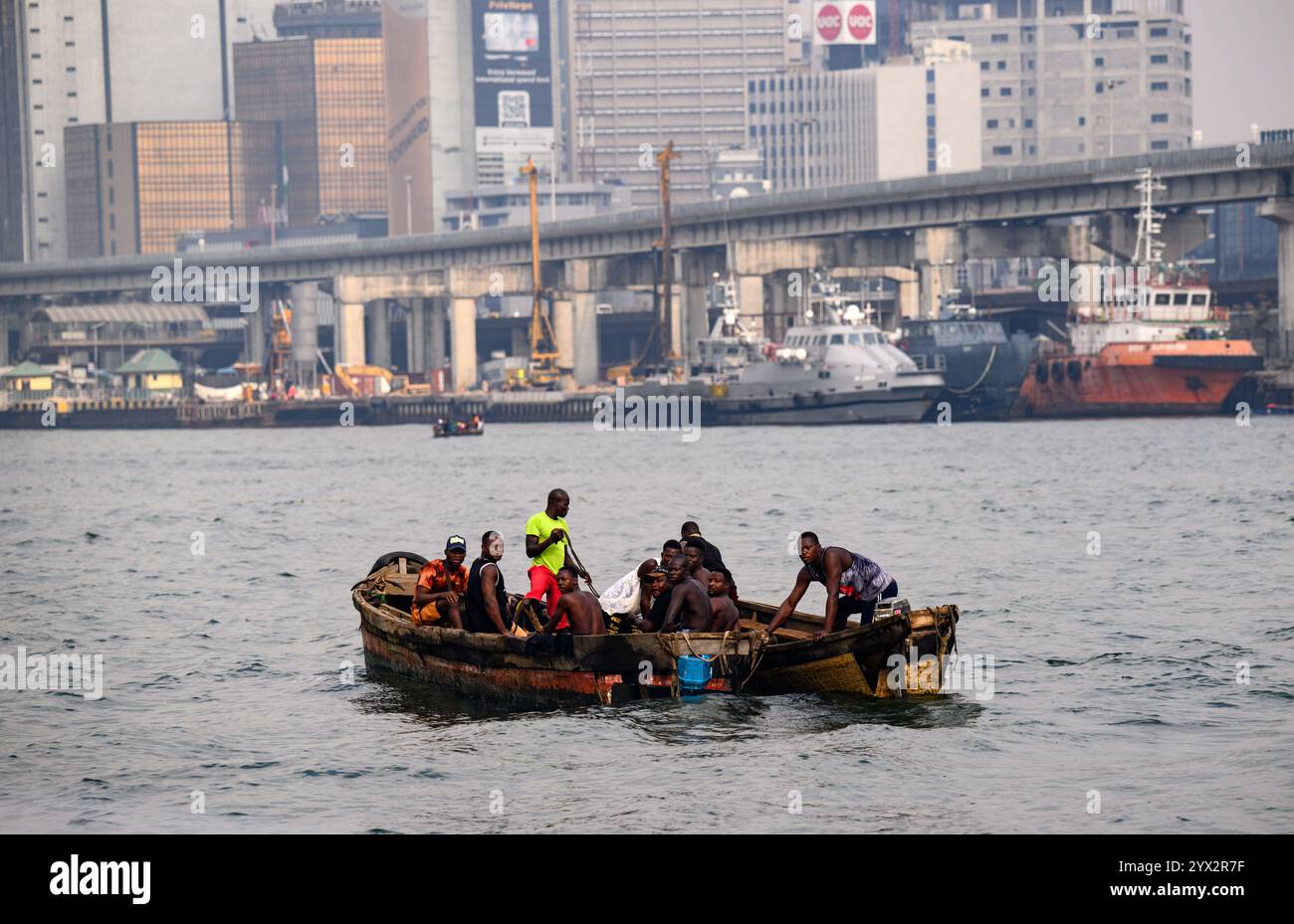 Lagos, Nigeria. Dezember 2024. Männer segeln auf Booten durch den Hafen von Lagos. Der Hafen von Lagos ist Nigerias ältester und größter Hafen. Mit schätzungsweise 25 Millionen Einwohnern ist Lagos Nigerias größte Stadt und eine der Mega-Metropolen Afrikas. Quelle: Bernd von Jutrczenka/dpa/Alamy Live News Stockfoto