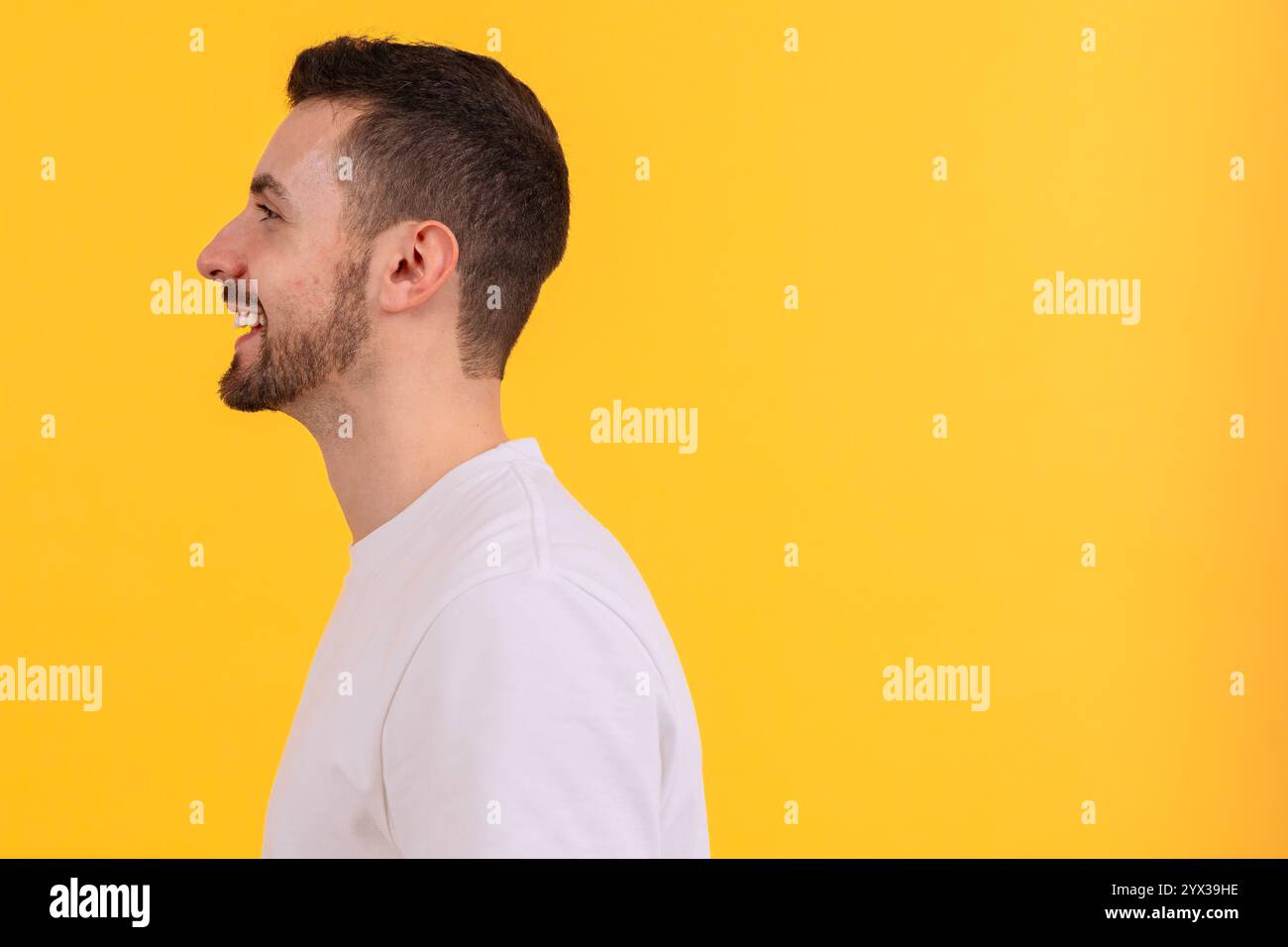 Seitenprofil eines lächelnden Mannes in einem weißen T-Shirt auf gelbem Hintergrund Stockfoto