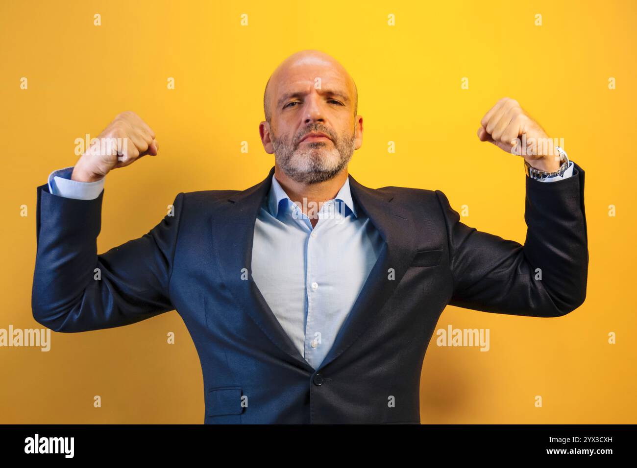 Ein Mann in einem dunkelblauen Anzug hebt seine Arme und zeigt Stärke. Stockfoto