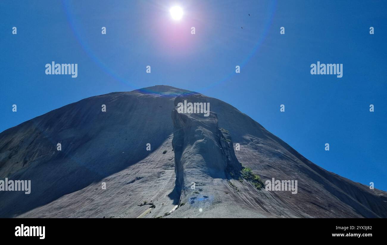 Der monumentale Blaue Stein mit der „Echse“ versucht, ihn dramatisch gegen einen unberührten, wolkenlosen blauen Himmel zu erklimmen Stockfoto