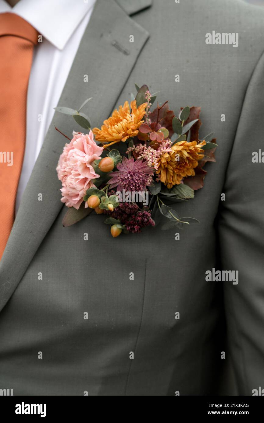 Boutonniere mit Blumenmuster und Herbsttönen auf grünem Anzug Stockfoto