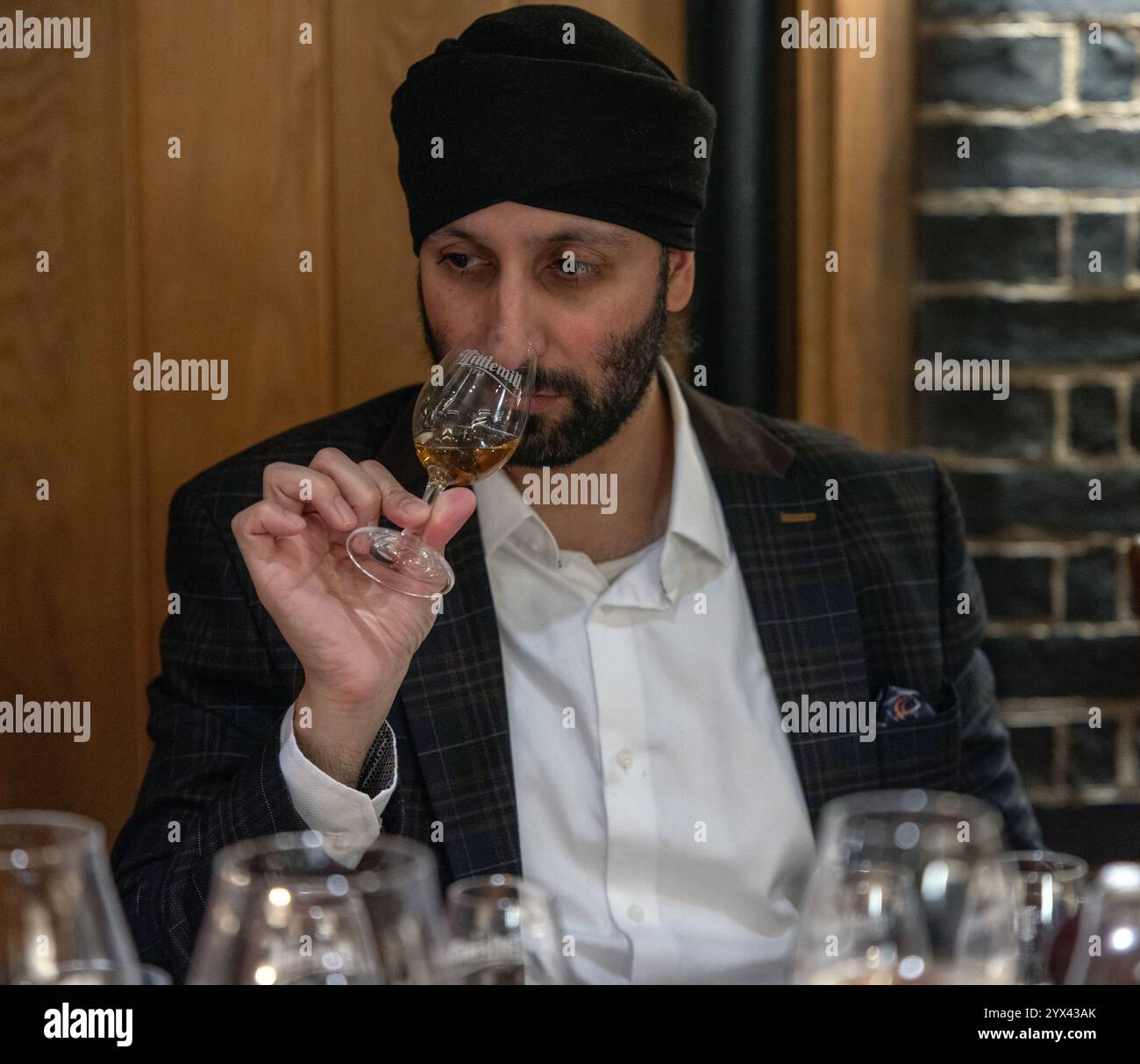 Indischer Mann, der ein Glas schottischen Malt Whisky "nasen" Stockfoto
