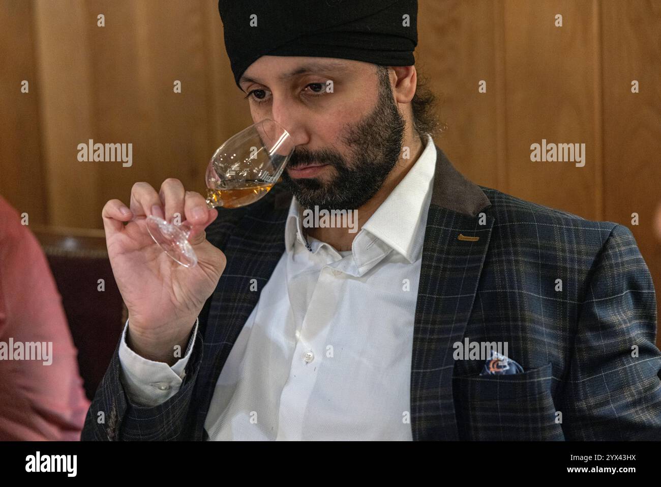 Indischer Mann, der ein Glas schottischen Malt Whisky "nasen" Stockfoto