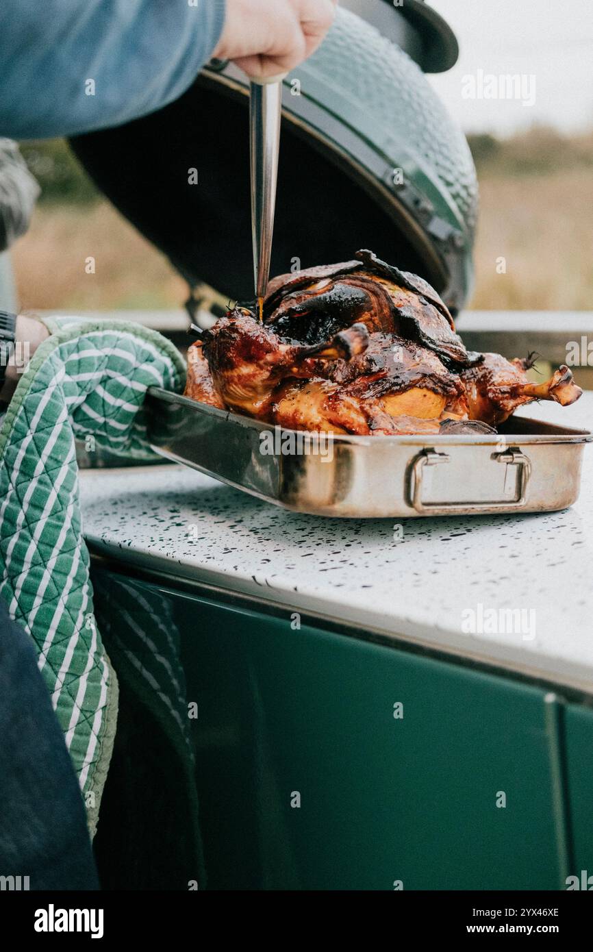 Eine Person kocht ein Huhn auf einem Grill. Das Huhn ist mit viel Soße bedeckt und er ist ziemlich groß Stockfoto
