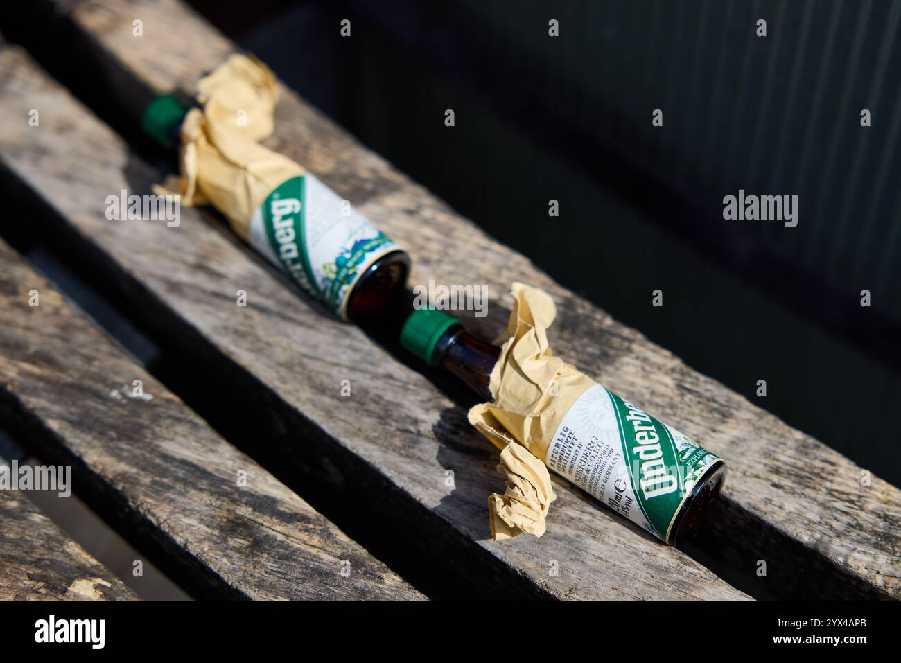 Kleine leere Flaschen Underberg (Digestif Bitter) auf einer Holzbank Stockfoto