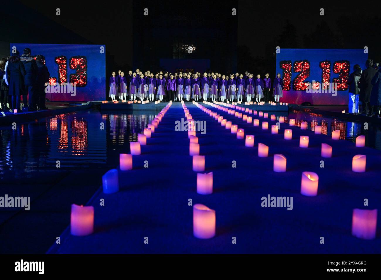 Nanjing, chinesische Provinz Jiangsu. Dezember 2024. Kinder singen ein Lied, während sie an einer Kerzenlichtwache in der Gedenkhalle der Opfer des Massakers in Nanjing, der Hauptstadt der ostchinesischen Provinz Jiangsu, am 13. Dezember 2024 teilnahmen. Am Freitag fand hier eine Mahnwache bei Kerzenlicht statt, um den diesjährigen Gedenktag für die Opfer des Massakers von Nanjing zu feiern. Quelle: Ji Chunpeng/Xinhua/Alamy Live News Stockfoto