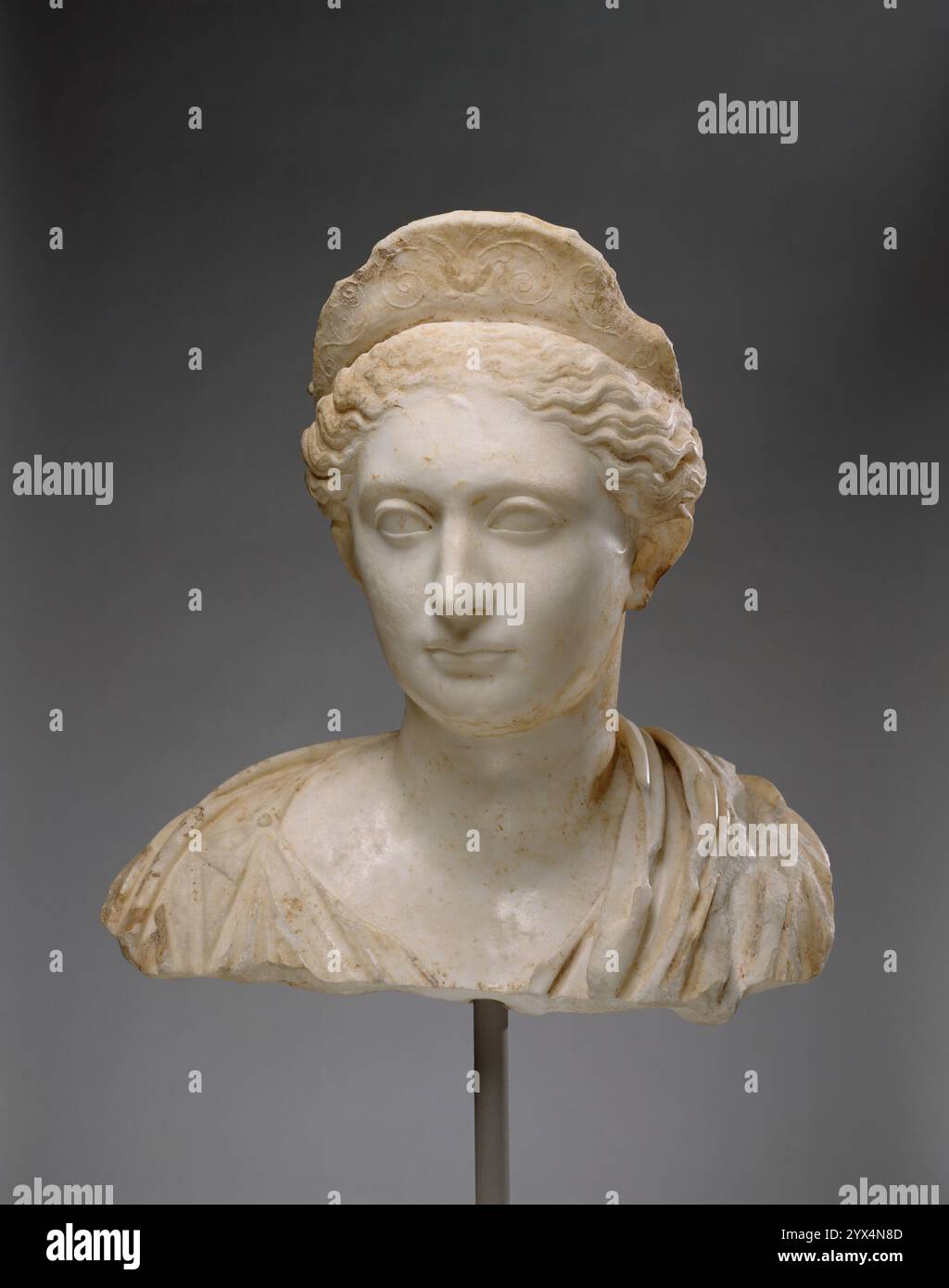 Die Büste einer Frau, ungefähr um 130 n. Chr. Das Porträt soll seit langem Sabina (83–137 n. Chr.), die Ehefrau des Kaisers Hadrian, darstellen. Besondere Merkmale wie die hervorstehenden Ohren lassen diese Identifikation zweifelhaft erscheinen. Ihr Haar ist in einem losen Brötchen befestigt, das normalerweise von griechischen Göttinnen getragen wird. Dies verleiht dem anonymen Sitter das Erscheinungsbild einer klassischen Statue, eine Einbildung, die durch das Diadem verstärkt wird. Stockfoto