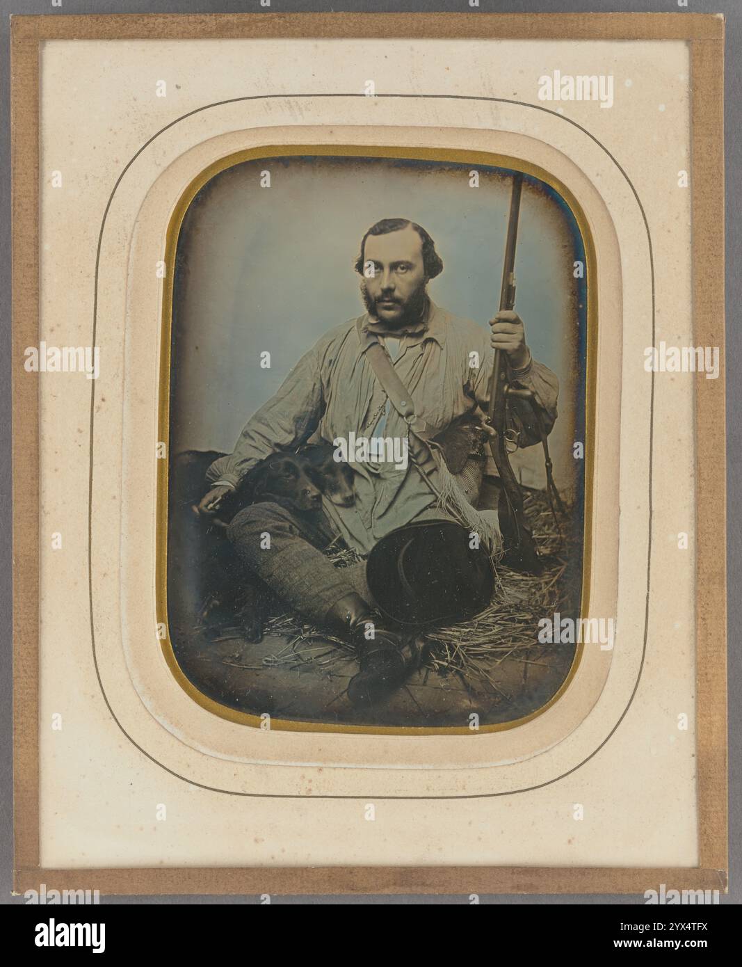 Bartjäger mit Pistole und zwei Hunden, ca. 1850. Weitere Informationen: Porträt eines Mannes, der in einem Studio auf einem Strohbett sitzt und ein Gewehr hält, mit zwei Hunden auf dem Oberschenkel. Stockfoto