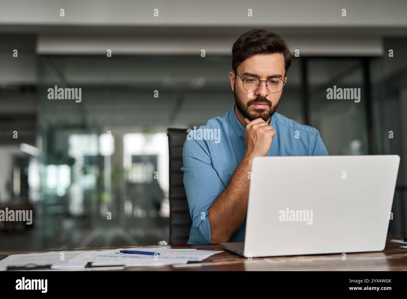 Beschäftigter junger Geschäftsmann, der über Online-Investitionen nachdenkt und an Notebooks arbeitet. Stockfoto