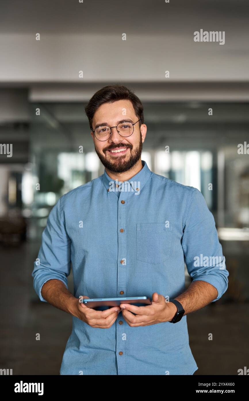 Glücklicher professioneller lateinamerikanischer Geschäftsmann, der bei der Arbeit auf die Kamera schaut, Porträt. Stockfoto