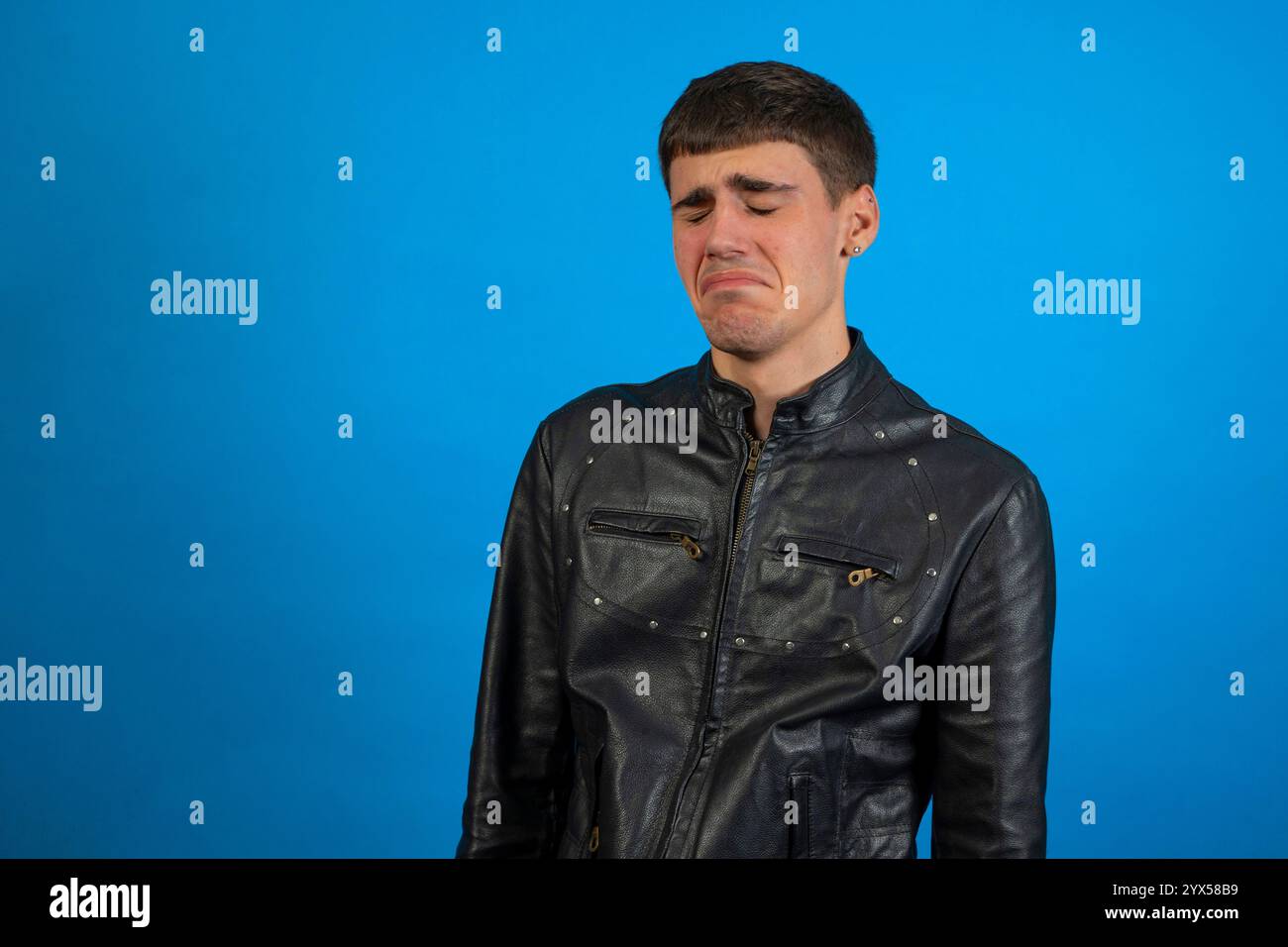 Trauriger Rocker fühlt sich blau an und weint wegen eines Herzschmerzes. Er leidet unter emotionalen Schmerzen auf einem normalen Studiohintergrund Stockfoto