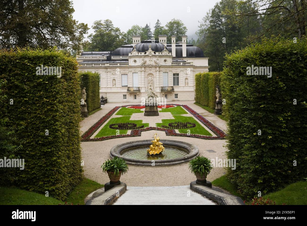 Hochwinkelblick auf Parterre mit Grenzen und Wasserbrunnen, die von Laubbaumhecken im formellen Garten des Linderhofs im Spätsommer begrenzt werden. Stockfoto