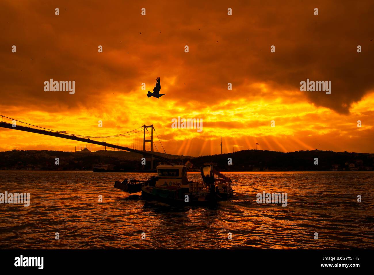 Das Reinigungsboot der Stadt Istanbul reinigt das Meer im Bosporus. Blick auf die Märtyrerbrücke vom 15. Juli und die Camlıca-Moschee bei Sonnenaufgang. Stockfoto