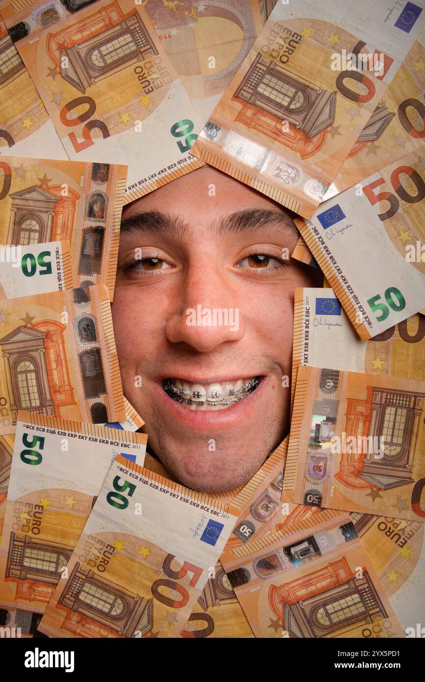 Ein junges Gesicht mit fröhlichen Zahnspangen, die zwischen den Euro-Banknoten herausgucken Stockfoto