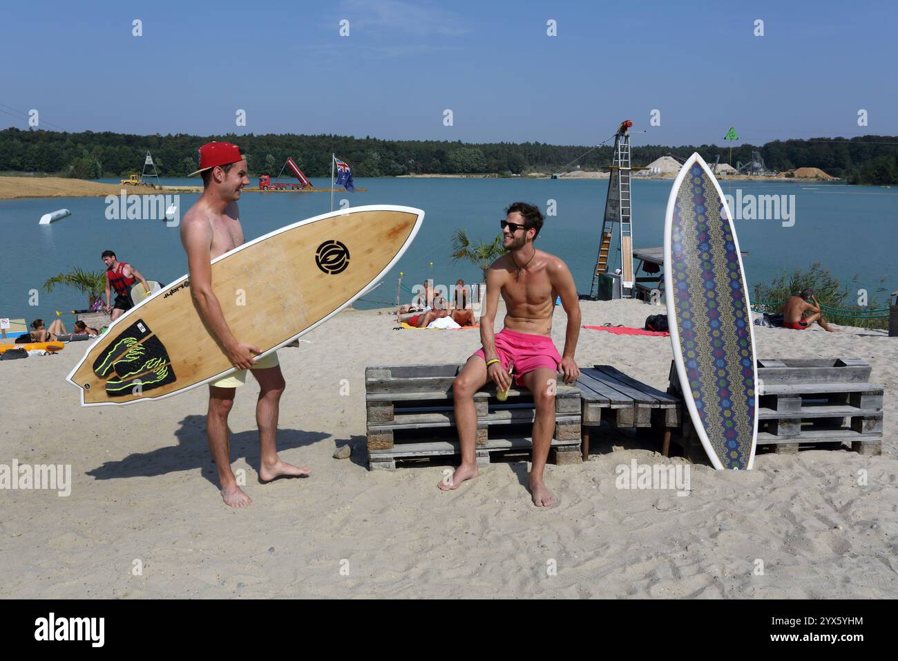 Zwei männliche Surfer genießen Sommersonne an einem kleinen Strand am Wakeport Rhein Main bei Raunheim, Hessen, Deutschland, Europa Stockfoto