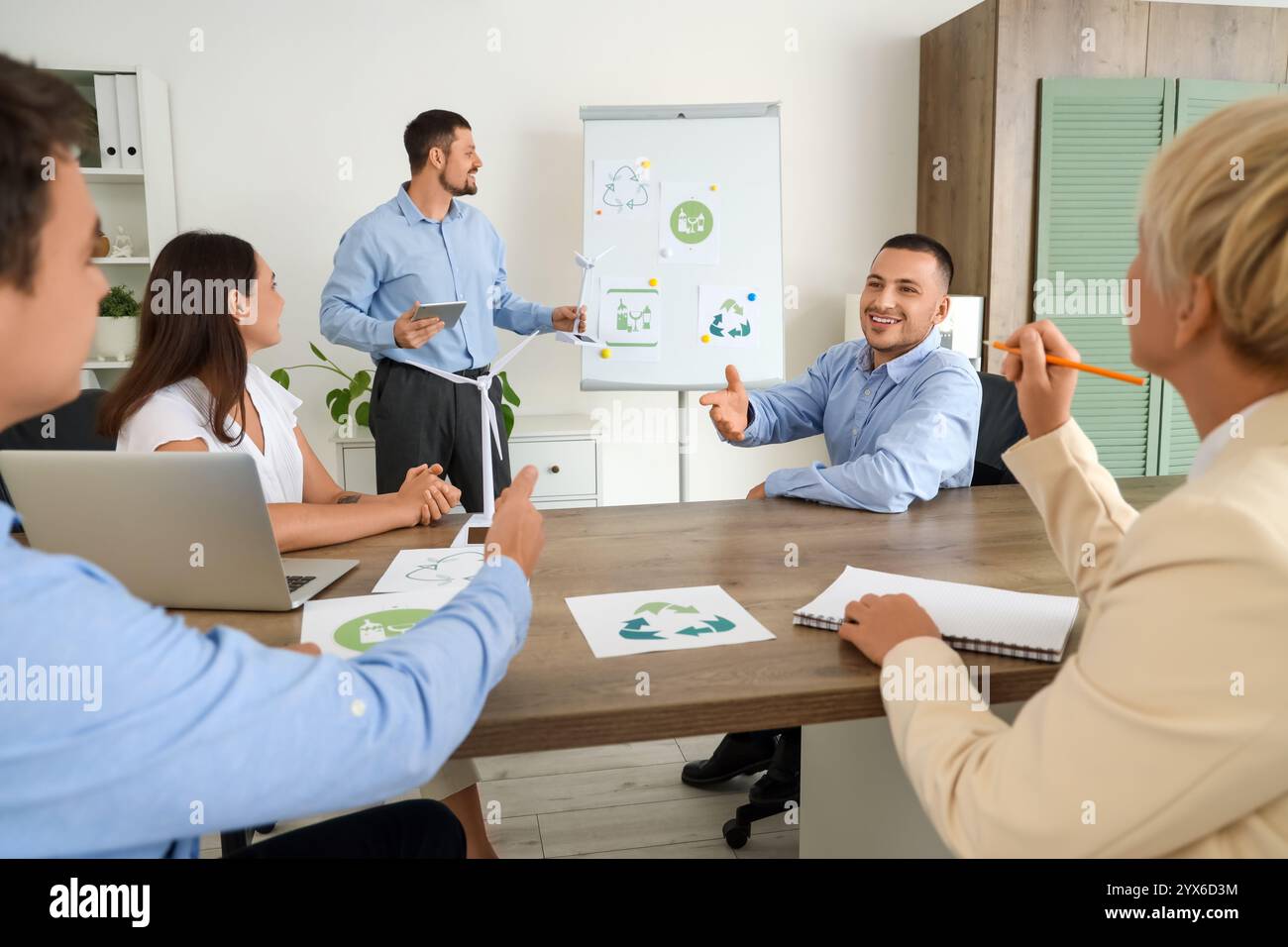 Männlicher Ingenieur mit Windkraftanlagenmodell, der seine Kollegen im Büro vorstellt Stockfoto
