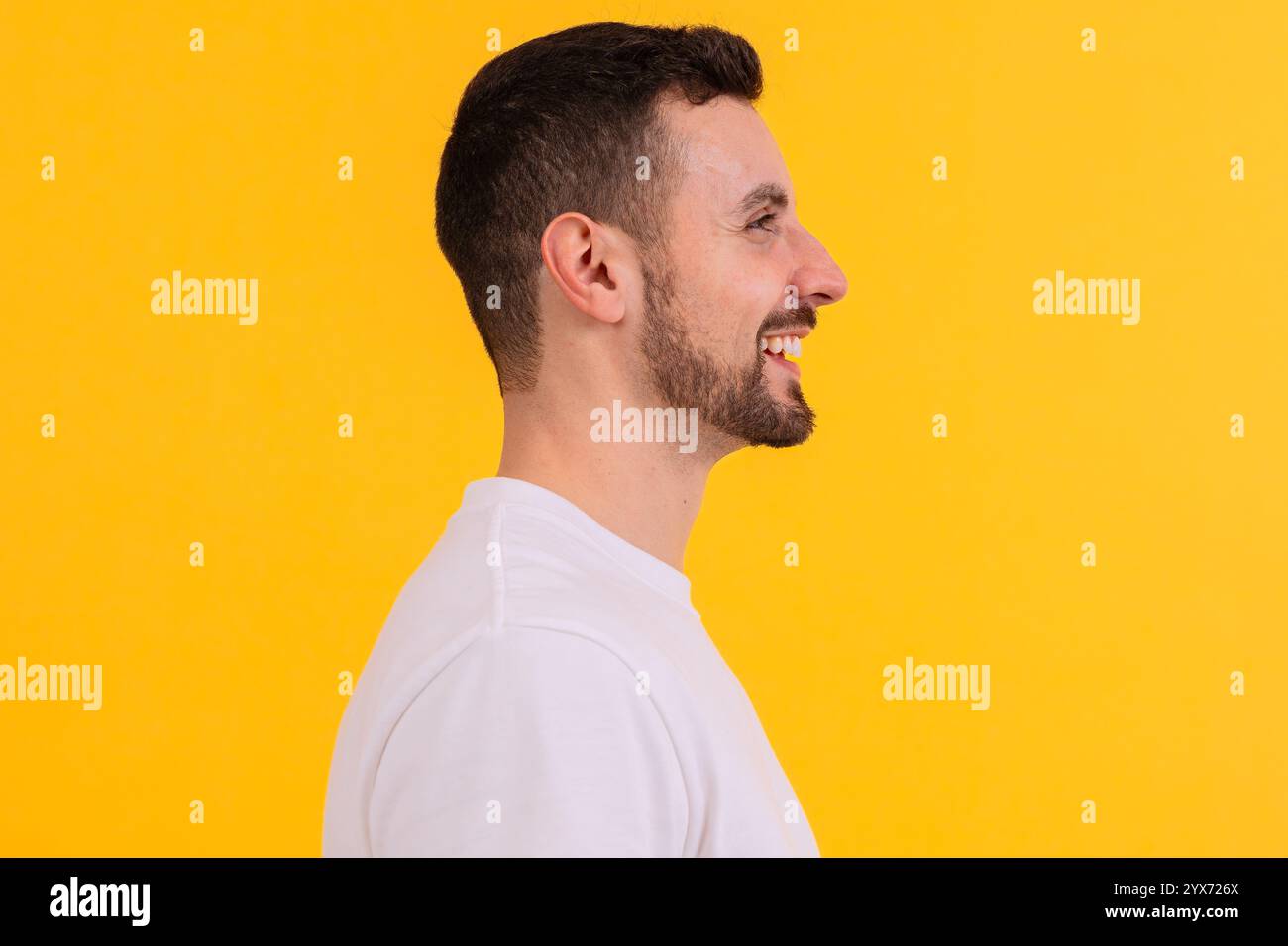 Seitenprofil eines lächelnden Mannes in einem weißen T-Shirt auf gelbem Hintergrund Stockfoto