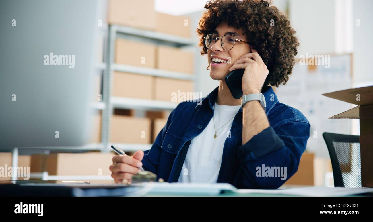 Computer, Telefonanruf und Versand mit Geschäftsmann im Büro für Lieferung, Verteilung oder Logistik. Box, Gespräch und Lächeln eines glücklichen Kuriers Stockfoto