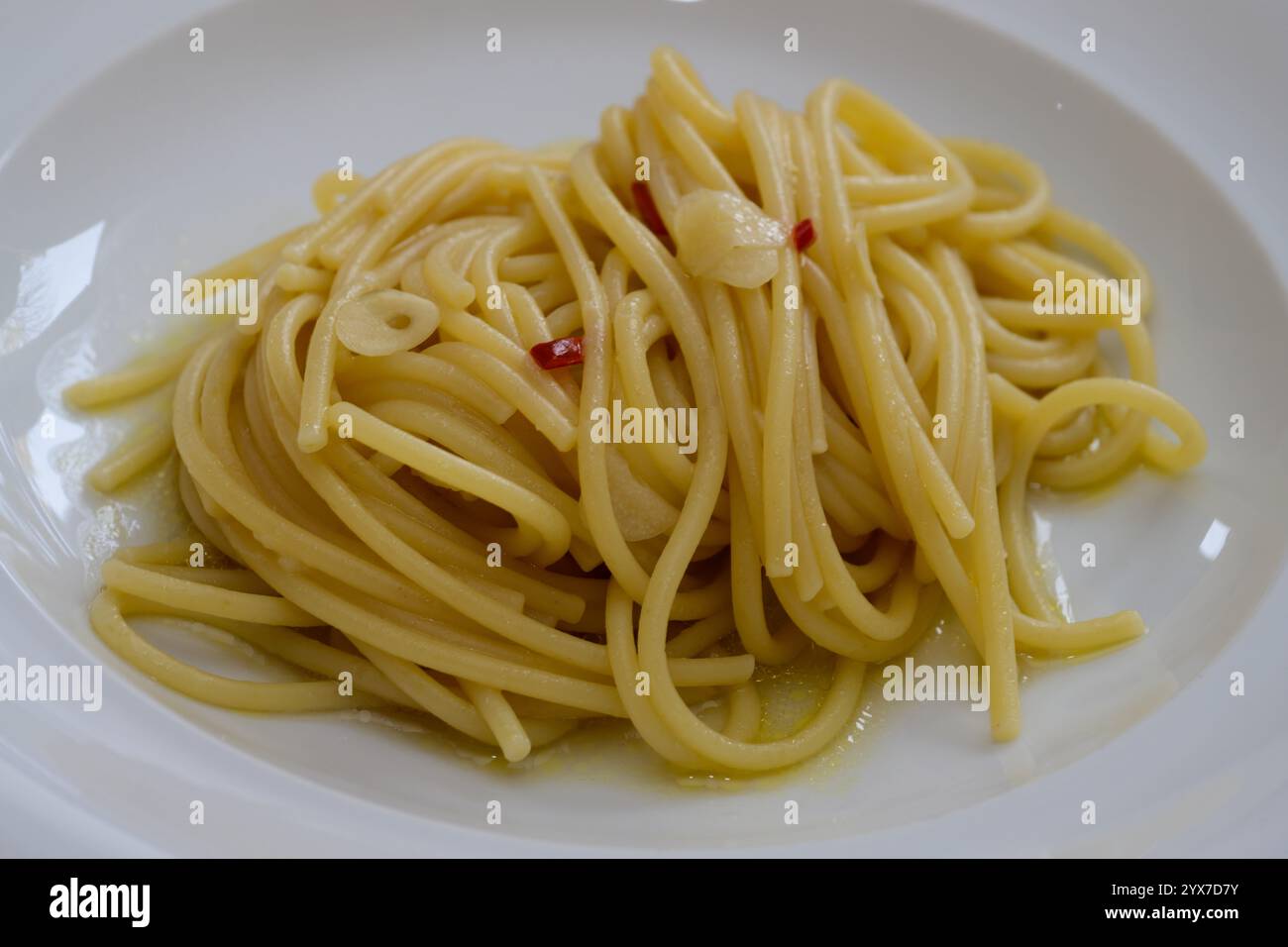Spaghetti Colatura di Alici mit Knoblauch und Peperoncini auf einer weißen Platte Stockfoto