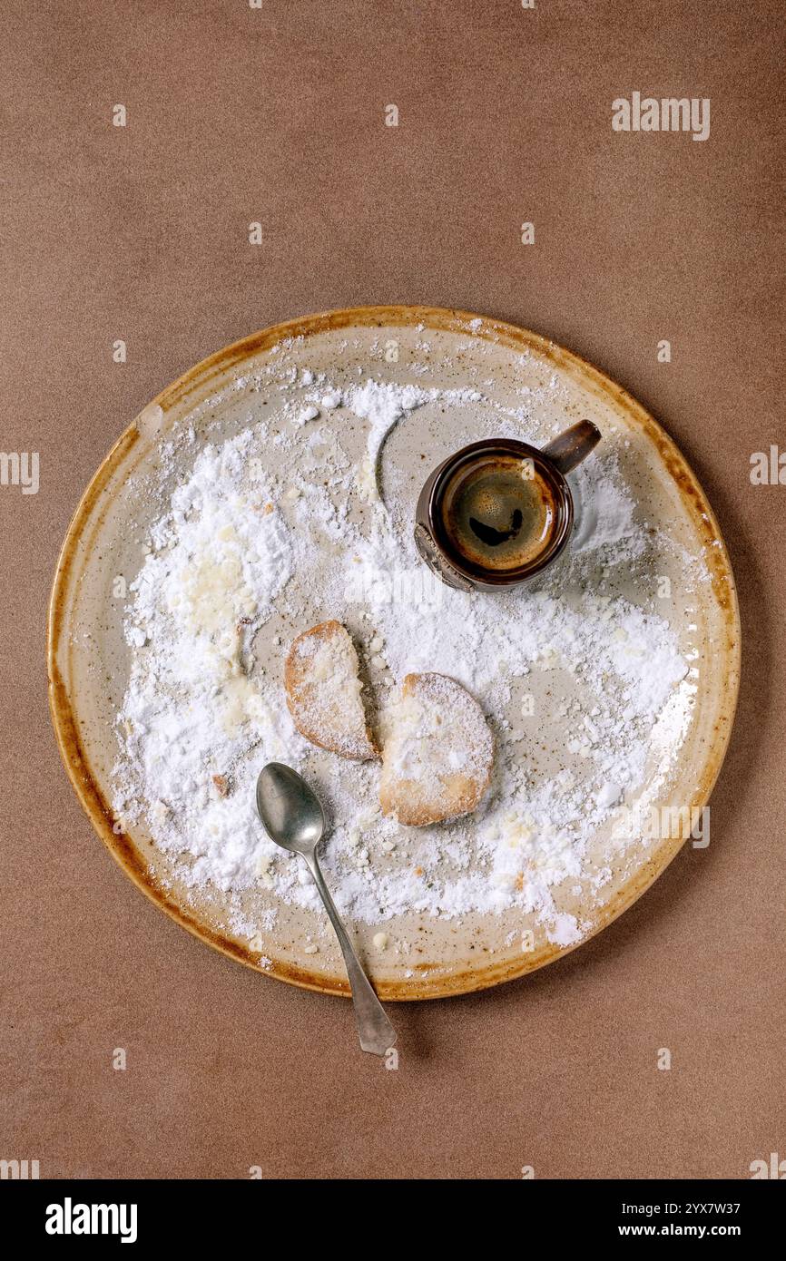 Letztes defektes Cookie. Hausgemachter Shortbread-Keks mit Puderzucker und einer Tasse frisch gebrühten Espresso. Hintergrund in der Farbe der Yea von 2025 Stockfoto