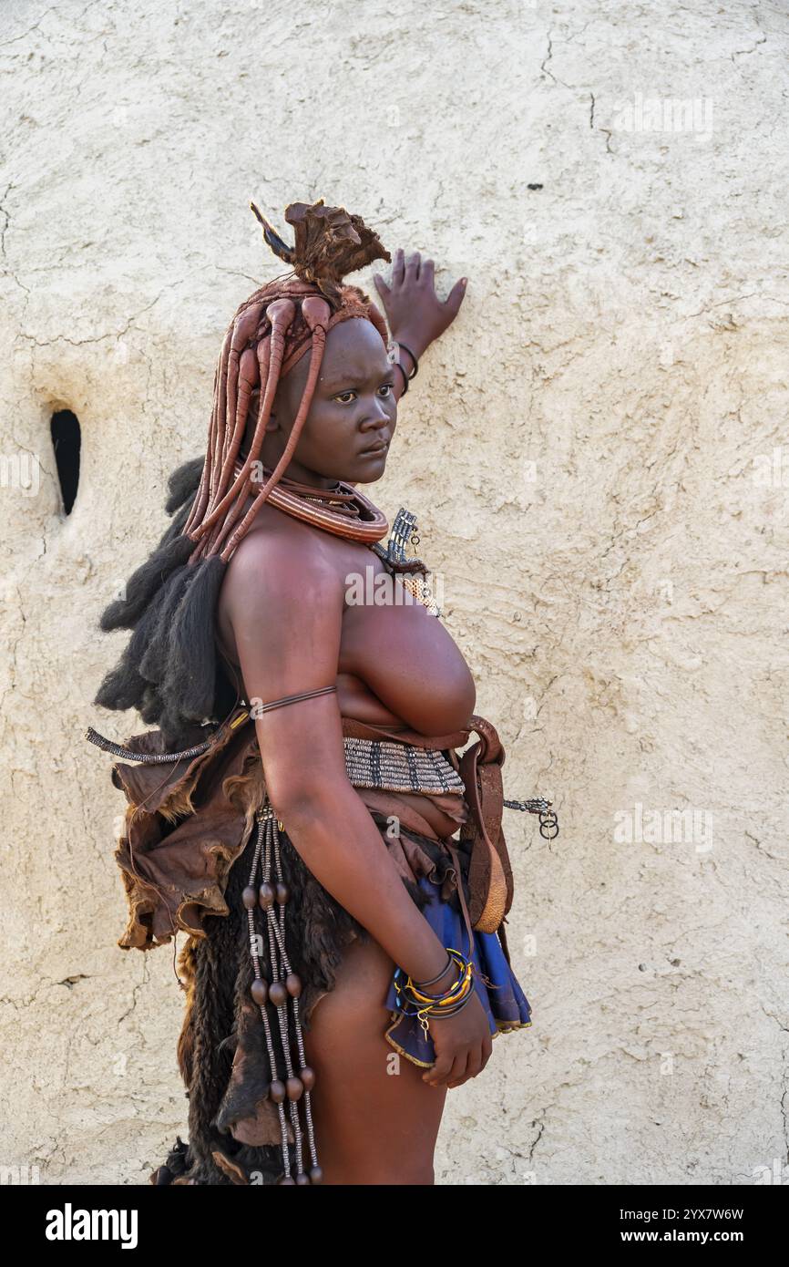 Verheiratet Himba-Frau, die sich an eine traditionelle Lehmhütte lehnt, am Morgen, traditionelles Himba-Dorf, Kaokoveld, Kunene, Namibia, Afrika Stockfoto