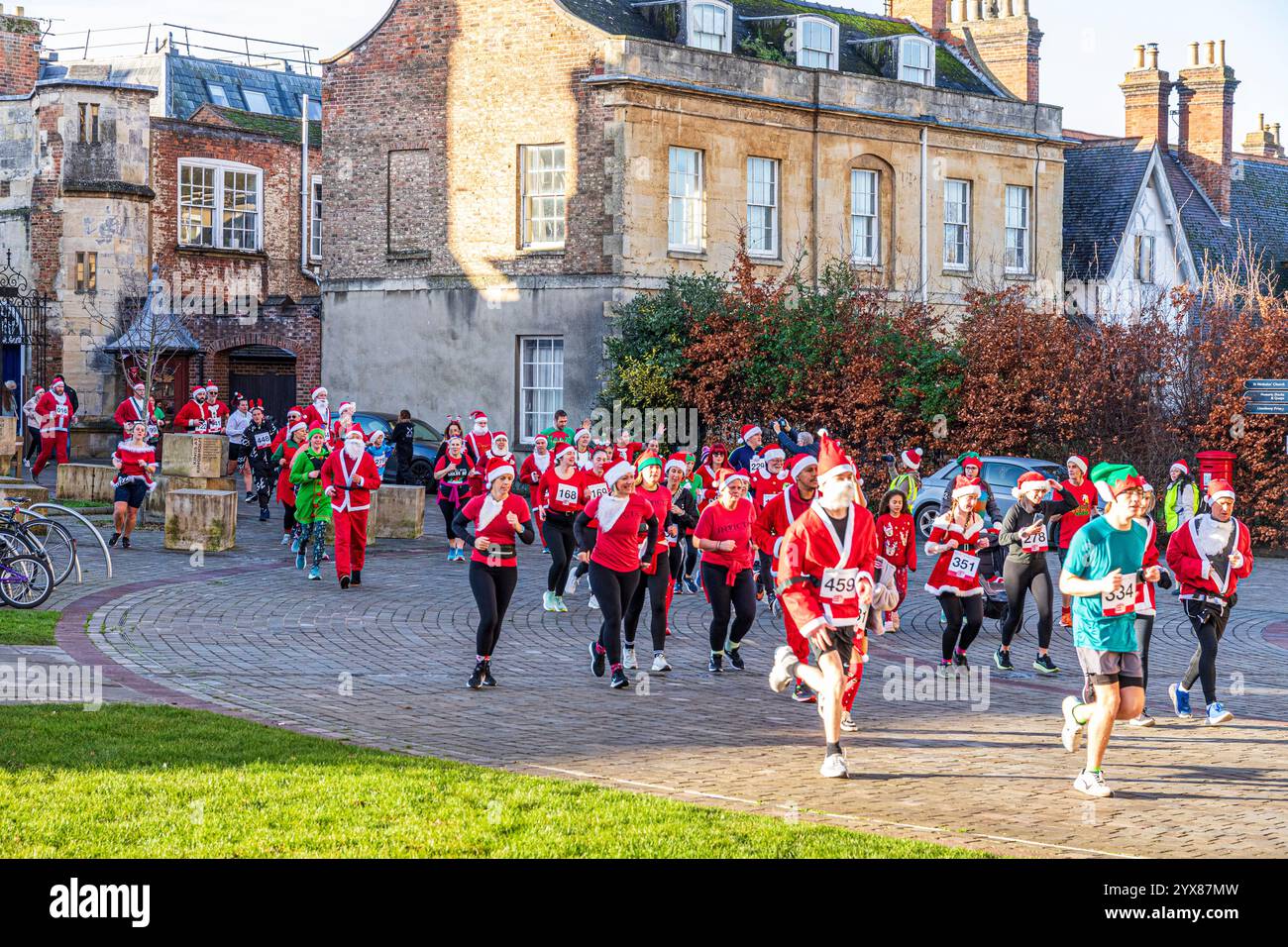 Einige der mehr als 600 Weihnachtsmänner, die die Kathedrale betreten, schließen während sie den Santa Fun Run laufen, der am 14./12/2024 von Rotary International in Gloucester, Großbritannien, organisiert wird Stockfoto