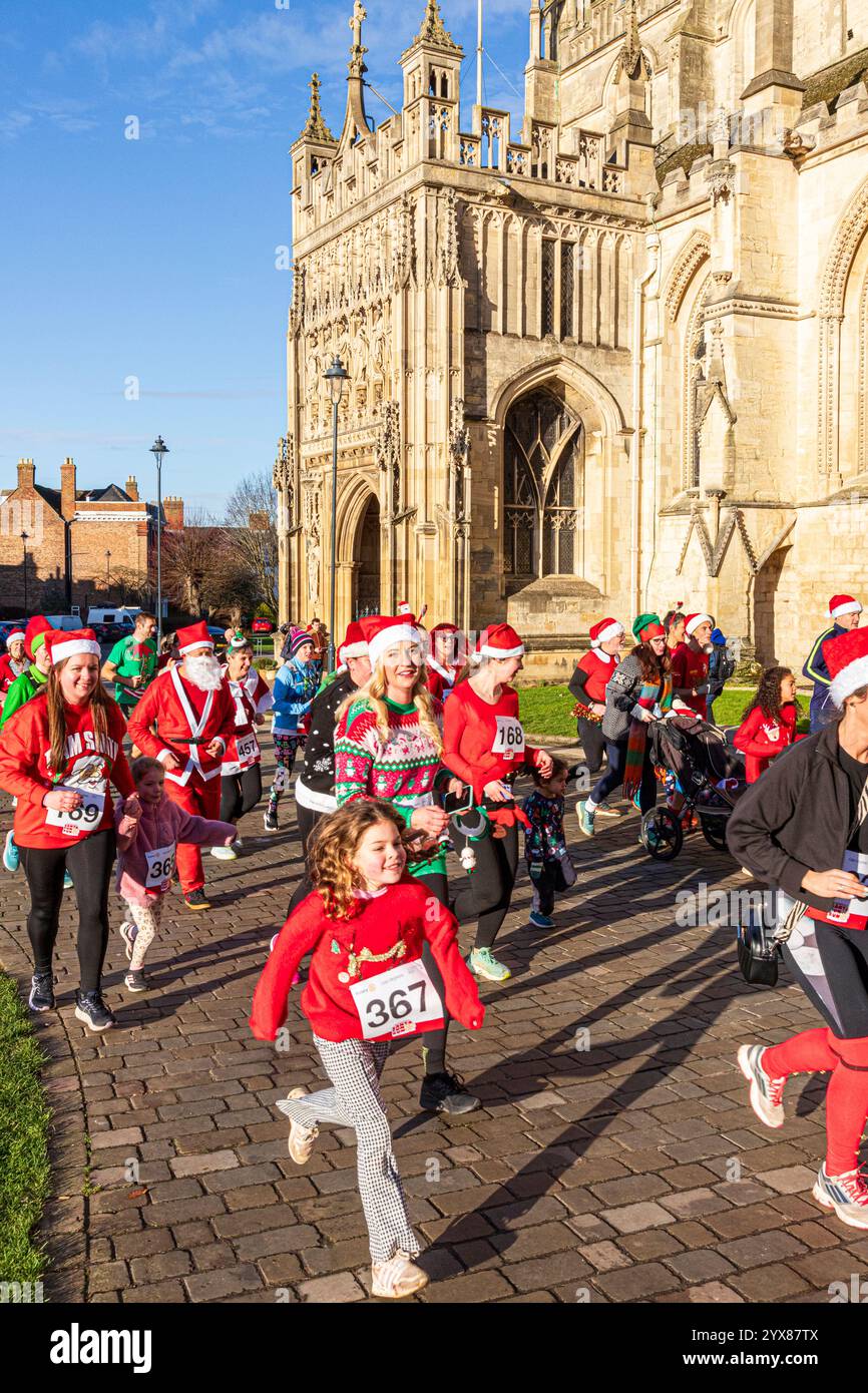 Einige der mehr als 600 Santas passieren die Kathedrale, während sie den Santa Fun Run laufen, der von Rotary International am 14./12/2024 in Gloucester, England U, organisiert wurde Stockfoto