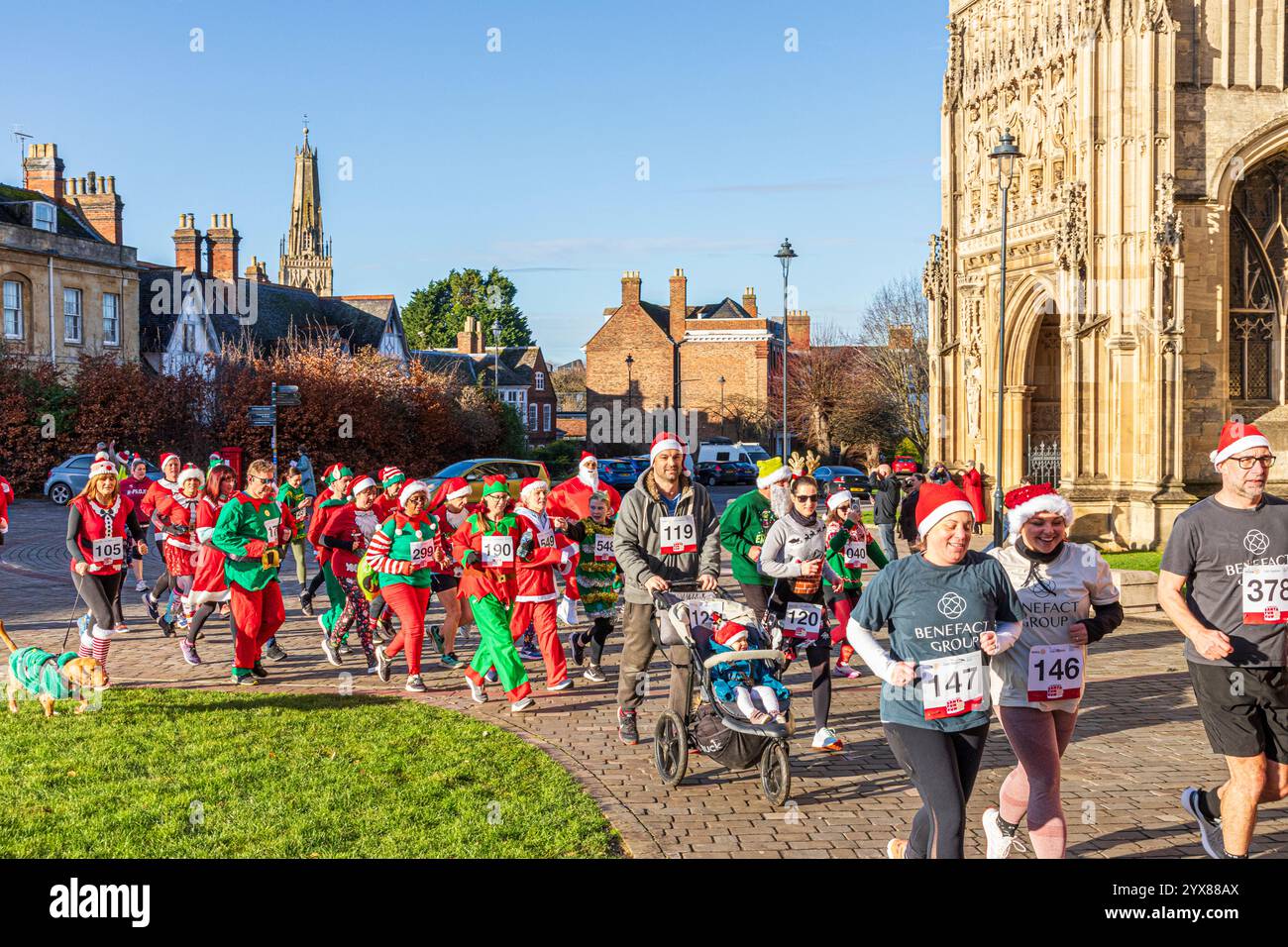 Einige der mehr als 600 Santas passieren die Kathedrale, während sie den Santa Fun Run laufen, der von Rotary International am 14./12/2024 in Gloucester, England U, organisiert wurde Stockfoto