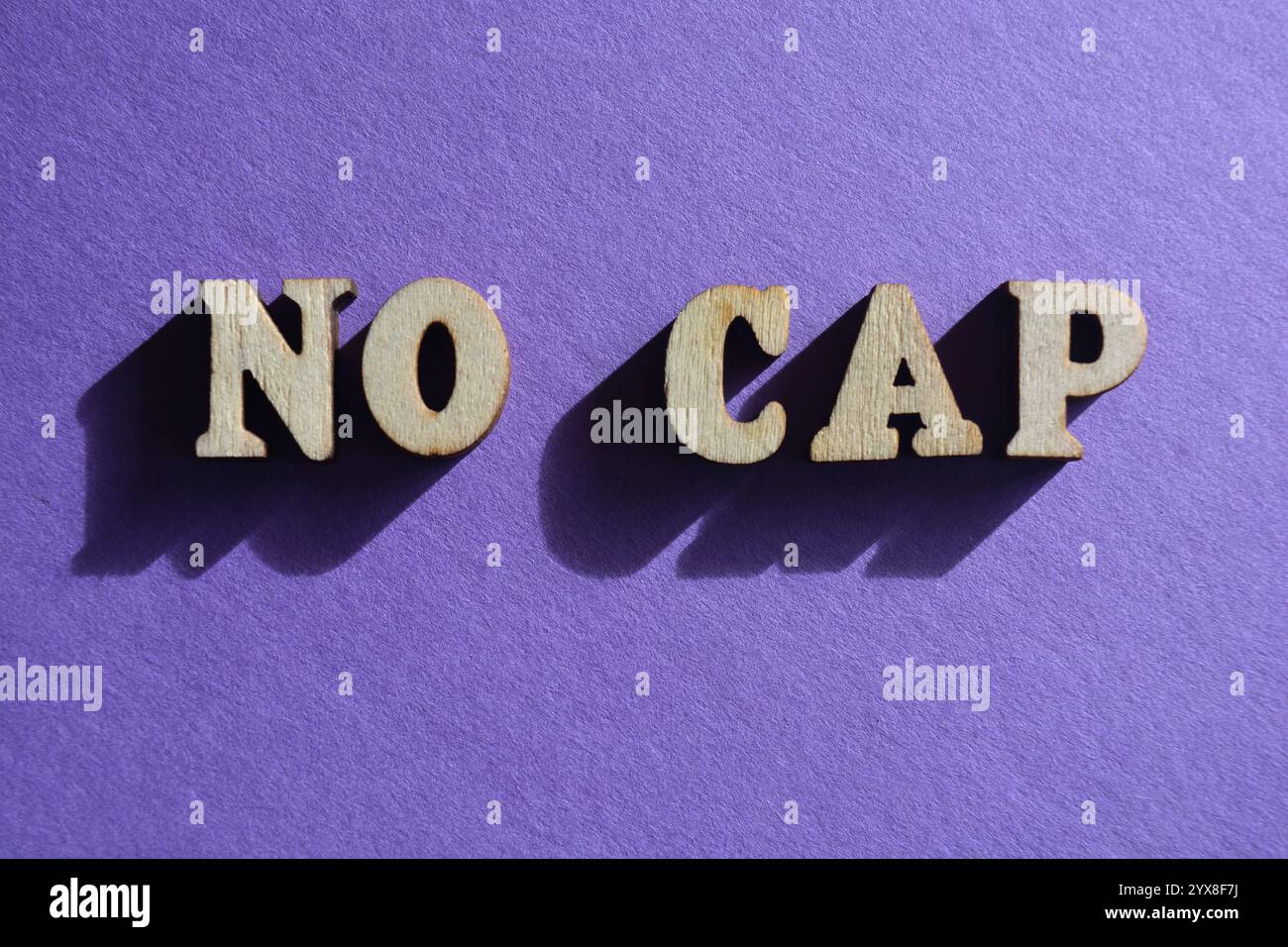 No Cap, kurzer Satz, der die Wahrheit ohne Übertreibung, ohne Lüge oder für echt in der Hip-Hop-Kultur bedeutet, in hölzernen Alphabeten isoliert auf lila bac Stockfoto