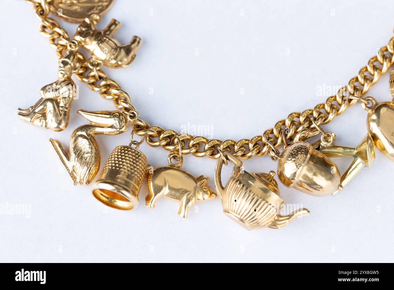 Nahaufnahme einer Sammlung von goldenen Charms auf einem 18 Karat Goldarmband Stockfoto