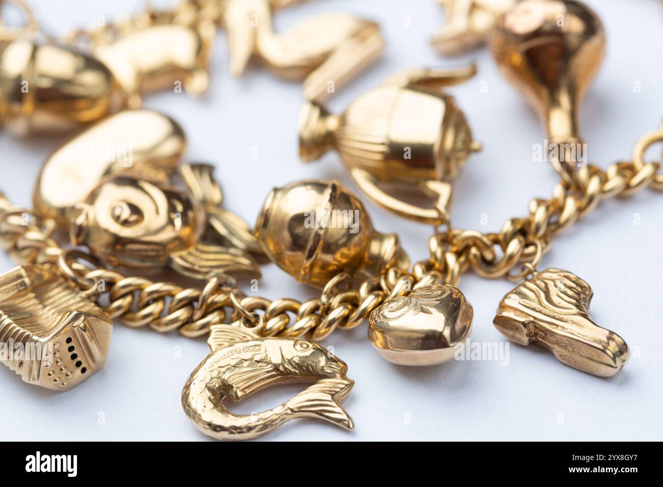 Nahaufnahme einer Sammlung von goldenen Charms auf einem 18 Karat Goldarmband Stockfoto