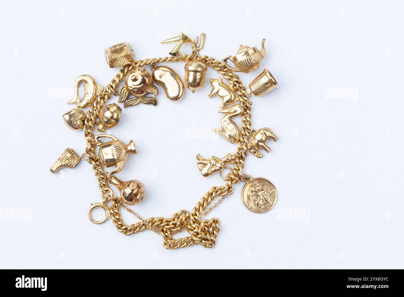 Nahaufnahme einer Sammlung von goldenen Charms auf einem 18 Karat Goldarmband Stockfoto