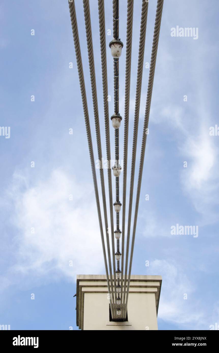 Die Aufhängungsseile und Lichter auf der Waco Hängebrücke erzeugen ein interessantes Muster vor einem blauen Himmel. Stockfoto