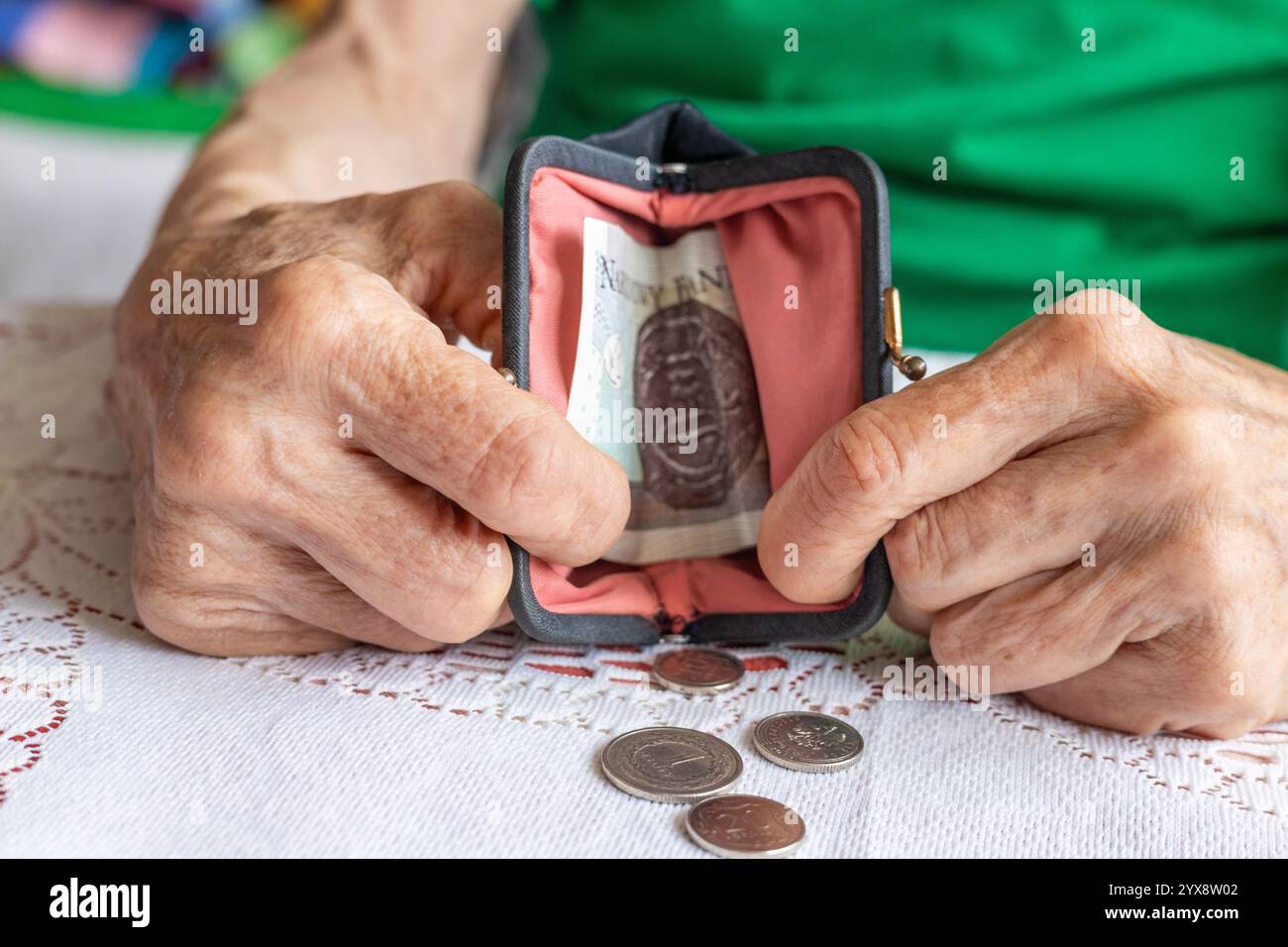 Eine polnische Seniorin mit berufsgetragenen Händen gießt Kleingeld aus ihrer Handtasche. Polnisch złoty. Finanzkonzept. Polen, Rentnerfinanzen. Nahaufnahme Stockfoto