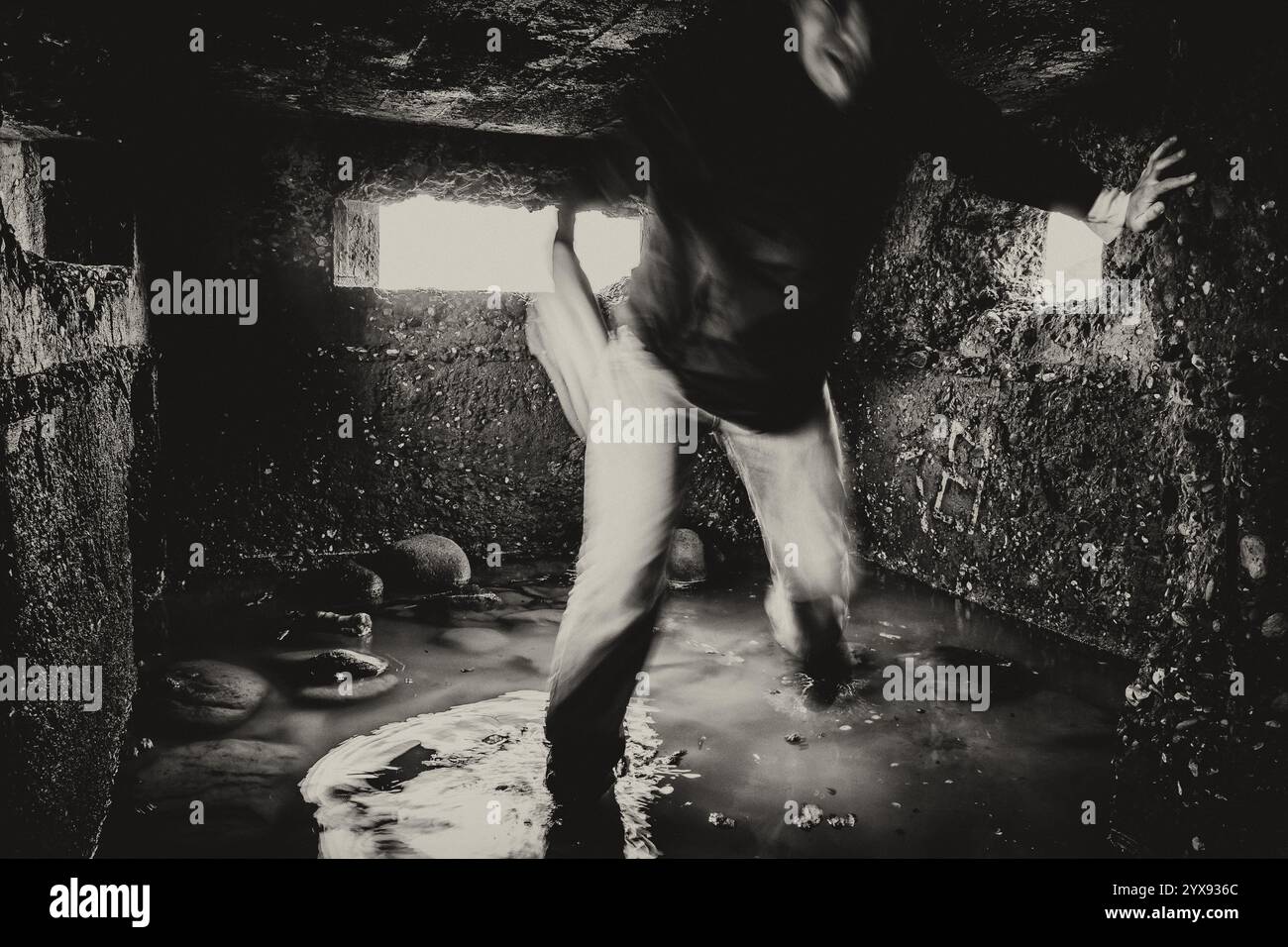 Ein Schwarzweiß-Foto einer gruseligen, verschwommenen Figur, die durch trübes Wasser in einem alten Pillenkasten aus dem 2. Weltkrieg auf die Kamera zustürmt Stockfoto