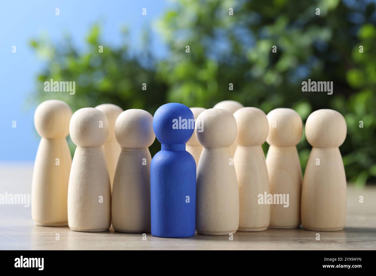 Personalkonzept. Blaue Figur unter hölzernen auf dem Tisch vor verschwommenem Hintergrund, Nahaufnahme. Leerzeichen für Text Stockfoto