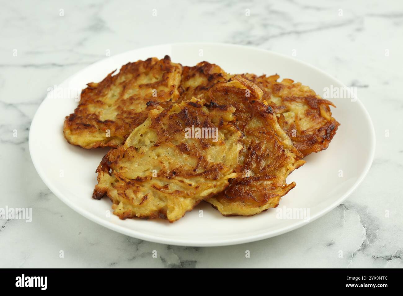Leckere Kartoffelpfannkuchen auf weißem Marmortisch, Nahaufnahme Stockfoto