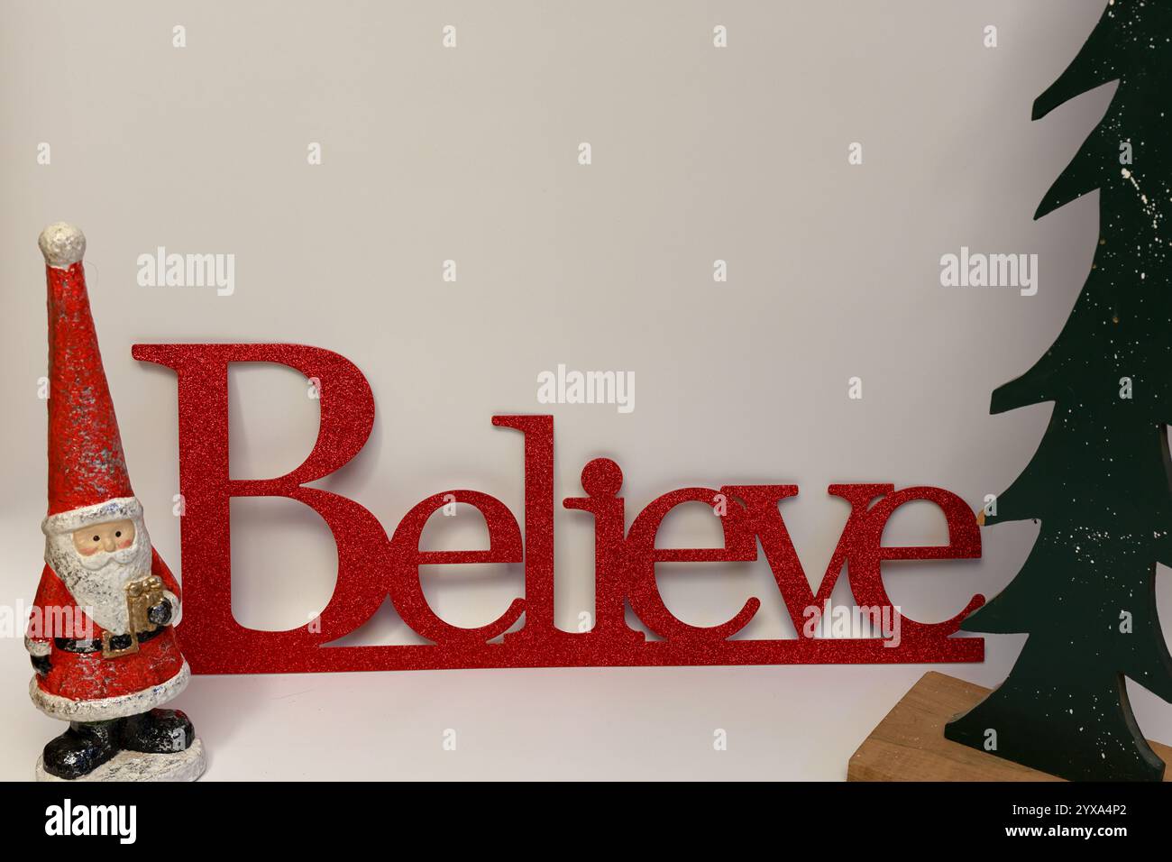 Das Wort glaubt neben einem geschnitzten Weihnachtsbaum mit einem sauberen, nahtlosen weißen Hintergrund Stockfoto