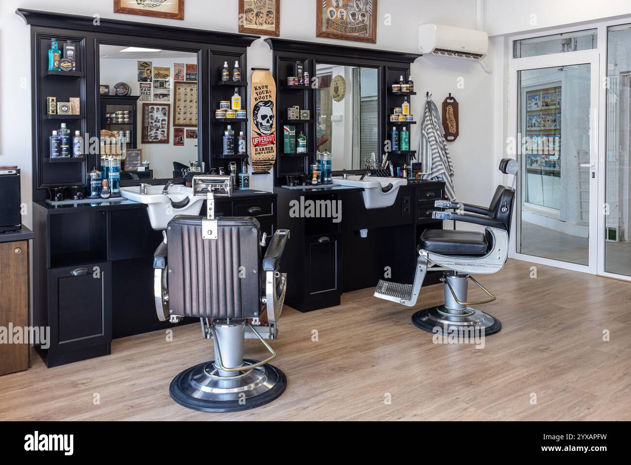 Zwei Friseurarbeitsplätze mit Stühlen von Belmont, schwarzen Schränken, Pflegeprodukten und Spiegeln schaffen eine stilvolle und professionelle Friseureinrichtung. Stockfoto