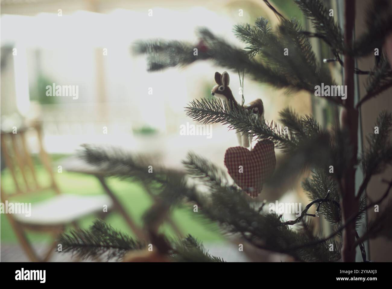 Nahaufnahme eines weihnachtlichen Rentiers und Herzschmuck, der an einem Weihnachtsbaum im Wohnzimmer hängt Stockfoto