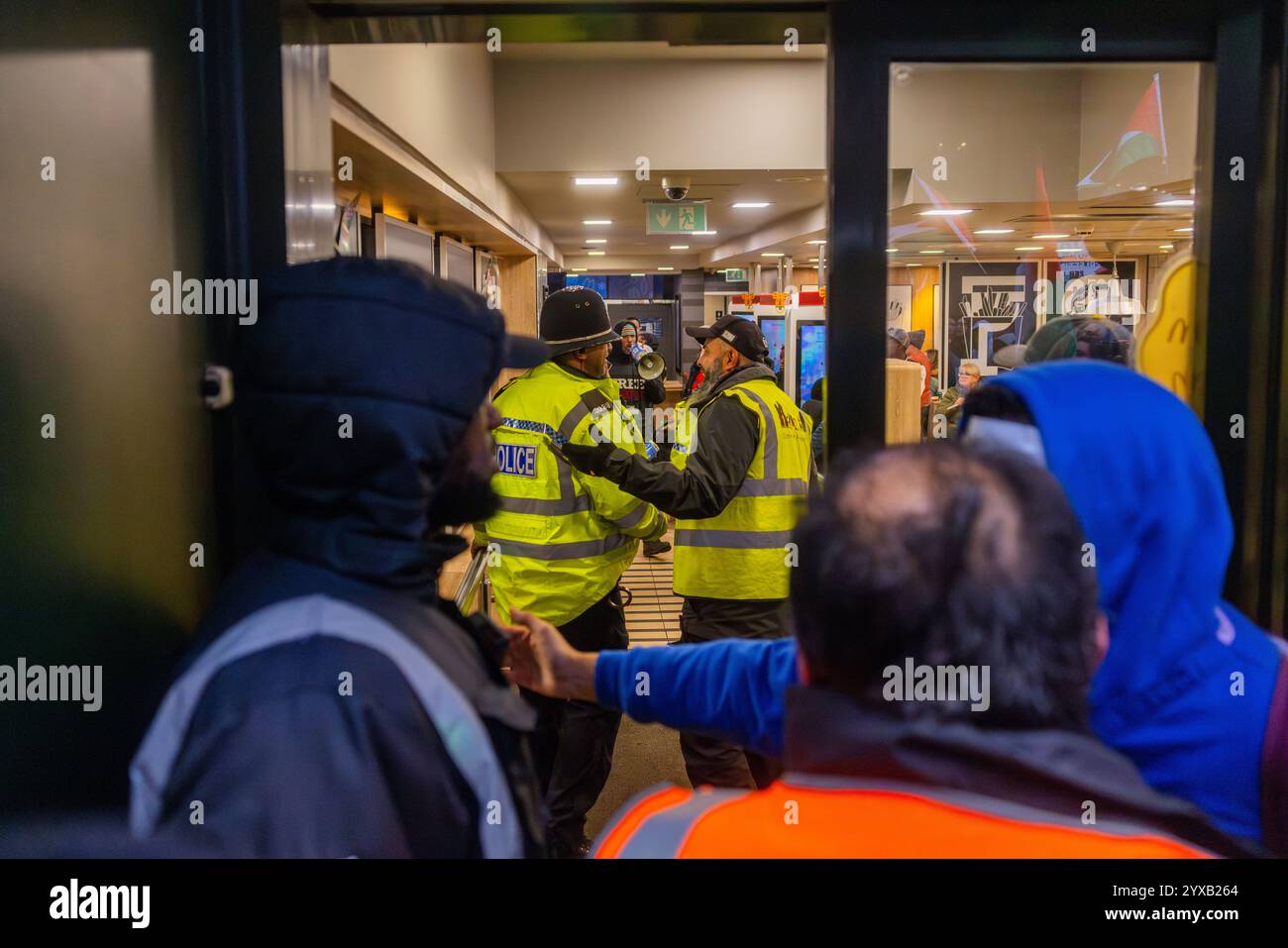 Birmingham, Großbritannien. DEZEMBER 2024. Demonstranten stürmen einen Zweig von McDonalds, während eine pro-Palestine-Menge vom Handsworth Park ins Zentrum von Birmingham marschierte. Die Gruppe, einschließlich derer, die als Teil von Healthworkers 4 Palestine Peelings trugen, sang und zündete Fackeln an. Gruppen aus Liverpool und London schlossen sich an. Credit Milo Chandler/Alamy Live News Stockfoto