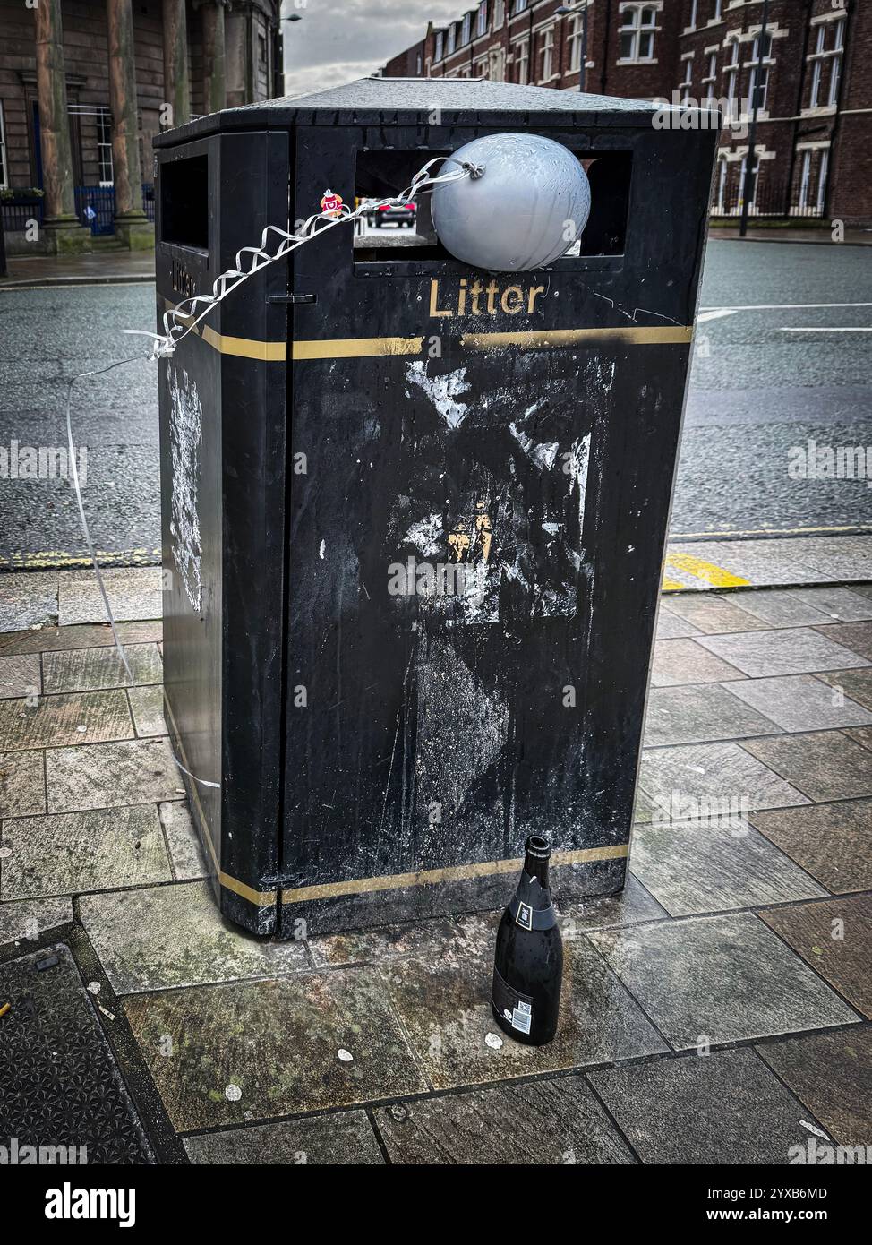 Mülltonne gefüllt mit aufgepumptem silbernem Ballon, daneben leere Flasche. Stockfoto