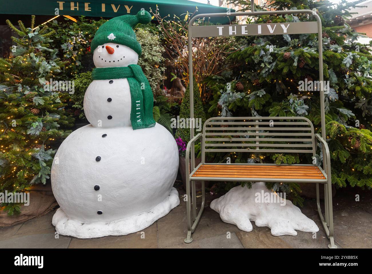 London, Großbritannien – 1. Dezember 2024, Covent Garden. Ein Schneemann mit grünem Hut und Schal steht vor Weihnachtsbäumen in der Nähe des Restaurants „The Ivy“ Stockfoto